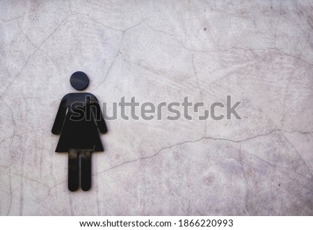 The image of a sign on cement wall room in front of the entrance to the female toilet.