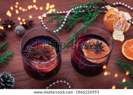 Two glasses of mulled wine with citrus fruits, star anise, nutmeg on wooden table. Seasonal Christmas mulled drink, New Year decorations, top view.