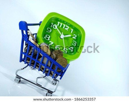 Selective focus.Green clock,coins and blue trolly isolated on white background.Business and holidays concept.