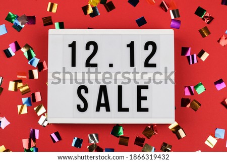 12.12 sale text on white lightbox and confetti on red background. Online shopping, singles day sale concept. Top view 