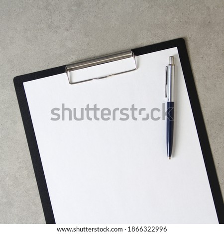 Template of white paper with a ballpoint pen on light grey concrete background in a black tablet with a clip. Concept of new idea, business plan and strategy, development and implementation of content