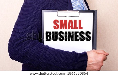 SMALL BUSINESS is written on a white sheet held by a man standing sideways