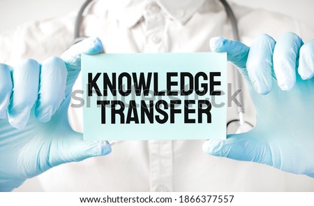 Doctor holding card in hands and pointing the word KNOWLEDGE TRANSFER