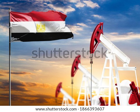 Oil rigs against the backdrop of the colorful sky and a flagpole with the flag of Egypt. The concept of oil production, minerals, development of new deposits.