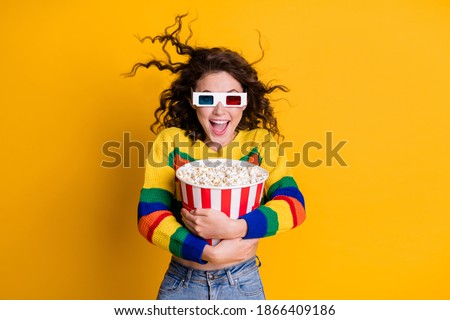 Photo of amazed funky young brunette hair lady hold popcorn watch tv wear spectacles sweater jeans isolated on yellow color background