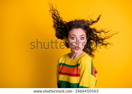 Photo of charming flirty woman dressed casual colorful sweatshirt wind blowing hair lips pouted isolated yellow color background