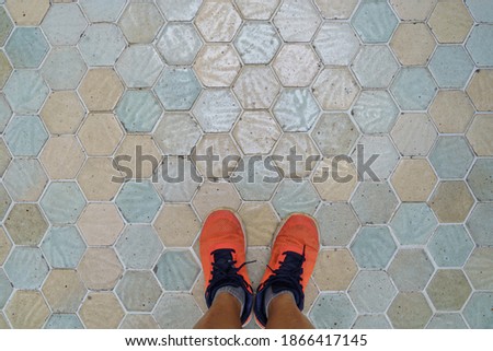 Top view of selfie orange shoe on vintage hexagonal mosaic ceramic tiles background. Selective focus on shoes.