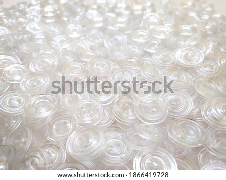 
Lots of white transparent buttons for clothes. Background on the theme of light industry. Plastic round buttons