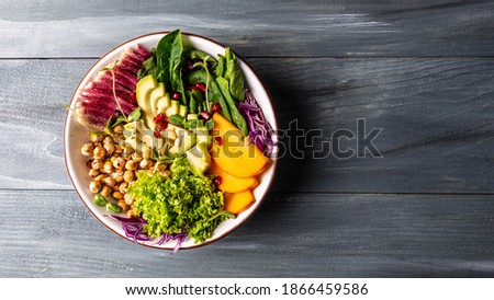 Fresh salad with roasted chickpeas, avocado, persimmon, spinach, avocado, watermelon radish and seeds. banner, catering menu recipe place for text, top view.