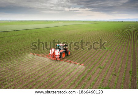 Tractor spraying pesticides on corn field  with sprayer at spring Royalty-Free Stock Photo #1866460120