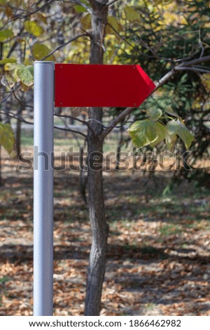 Red road road sign arrow in the park with empty space for text vertical