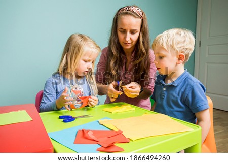 Little kids make a colorful poster with a tutor