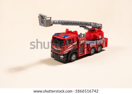 Toy typewriter on beige background red fire truck made of plastic. For the toy store, a gift for the boy