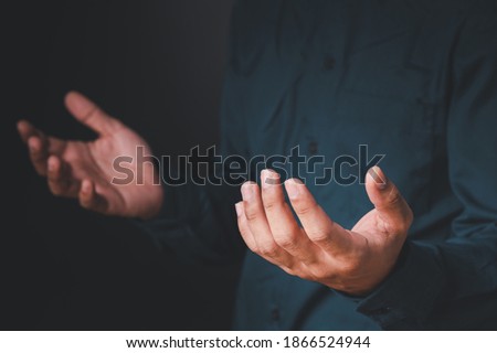 ฺBusiness man wearing a blue shirt. Showing hand symbols in various gestures On a black backdrop.