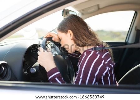 Profile of a young female driver looking sad behind the wheel because her car won't start and has mechanical problems in the middle of the highway Royalty-Free Stock Photo #1866530749