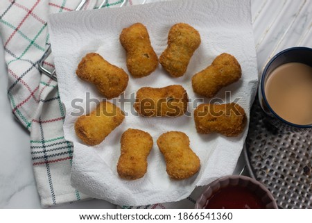 Stock photo of Fried crispy chicken nuggets with ketchup and cup of tea on white plate 