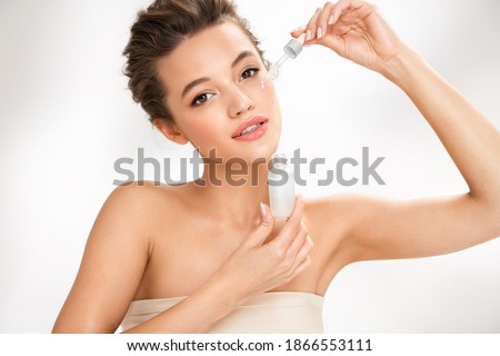 Woman applying  hyaluronic serum on her face with pipette. Photo of attractive woman with perfect makeup on white background. Beauty concept