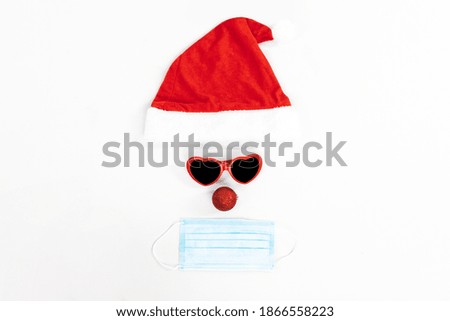 Christmas Santa Claus hat with medical mask to protect against coronavirus, with Christmas goggles on white background, concept of Christmas and New Year, Covid-19