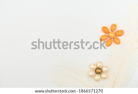 Flowers made of chocolate beads with feathers on white background. Mother day, Valentine day, Wedding, Birthday or other suitable event celebration card concept. Flat lay with copy space for your text