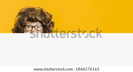 Happy child boy holding looks through a piece of paper for text