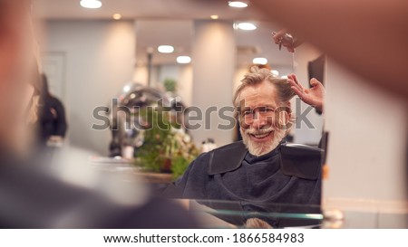 Senior Man Having Hair Cut By Female Stylist In Hairdressing Salon