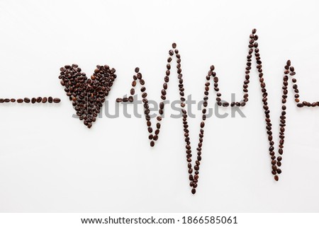 Coffee beans form a heart and a heartbeat curve on a white clean background.