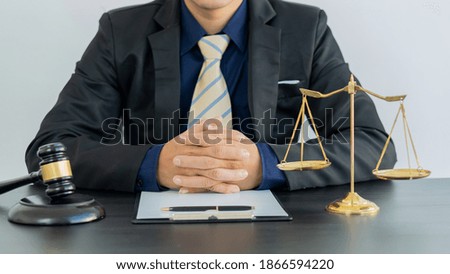 Concept of justice and law male judge in courtroom with mallet and scales with papers on the table