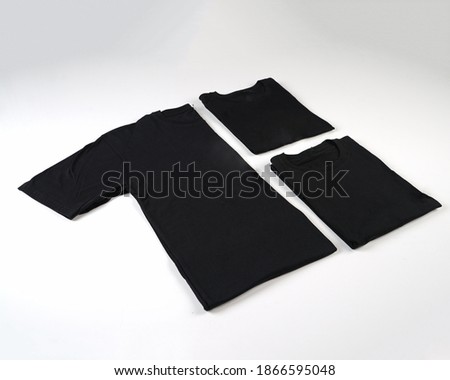 Black plain cotton shortsleeve crewneck t-shirt shot unfolded and folded in three different ways as a set isolated on white background. Three folded t-shirts. Converted in black and white.