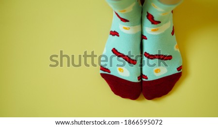 background of bright blue socks with a pattern of eggs and bacon on a yellow background                             