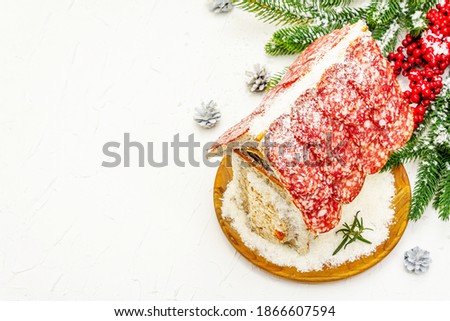 Charcuterie chalet or The Meat Hut as Christmas newest food trend. New Year Keto gingerbread house with traditional decor and symbols. White putty background, copy space