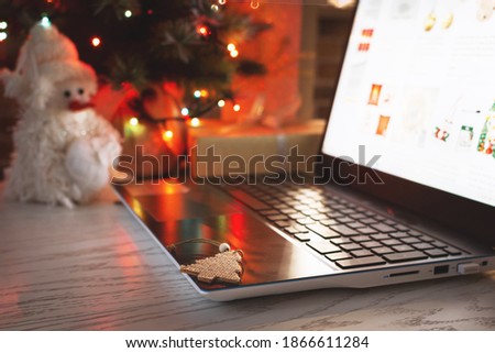Christmas shopping online. Laptop on table at home on the background of a Christmas tree with blurred bokeh lights.