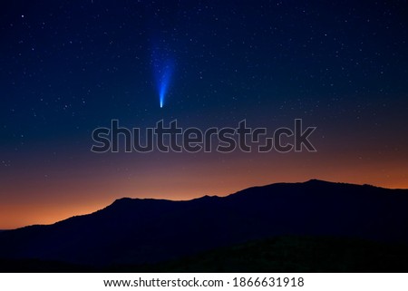 Comet Neowise above the mountains and bleeding light from the city