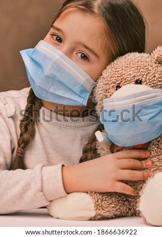 Little girl child holding a teddy bear wearing a mask. Concept of health care and virus protection covid. High quality photo