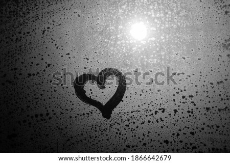 Close up hand drawing of a heart on a natural foggy window glass background. Valentine's day inspiration, close-up photo. An emotional sense of hope and love