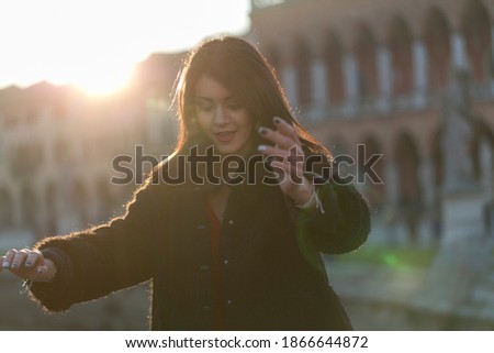 beautiful girl with long mediterranean black hair at sunset in the square of padua. High quality photo