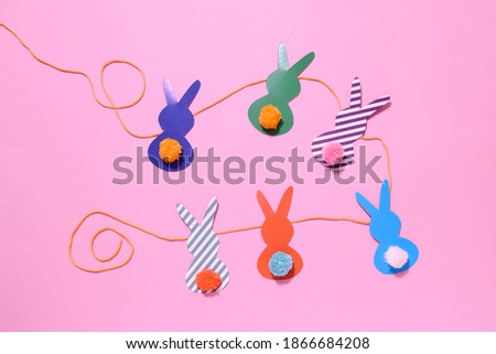 happy easter garland from paper rabbits with colored pompon tail. DIY concept and home decor