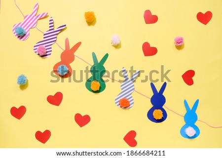 happy easter garland from paper rabbits with colored pompon tail. DIY concept and home decor