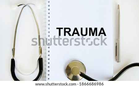 In the notebook is the text of TRAUMA, next to the stethoscope.