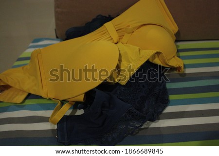 Beautiful close-up shot of the yellow bras set and deep blue bras set for women underwear on the colorful patterns bed sheet. 
