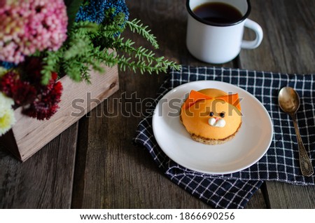 Children's dessert cake in the form of a beast cat on a plate with flowers. Dark food photography on wooden rustic background