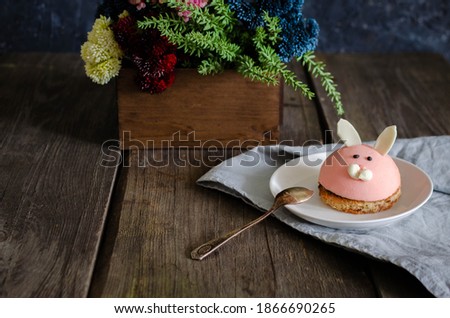 Children's dessert cake in the form of a beast hare on a plate with flowers. Dark food photography on wooden rustic background