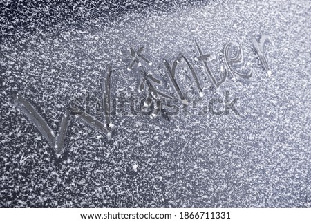 Inscription winter with a picture of a Christmas tree on frosty glass