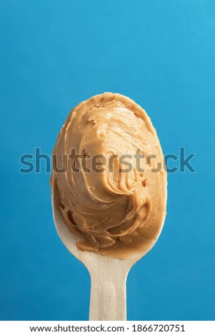 Spoon of nut oil on a blue background. 
