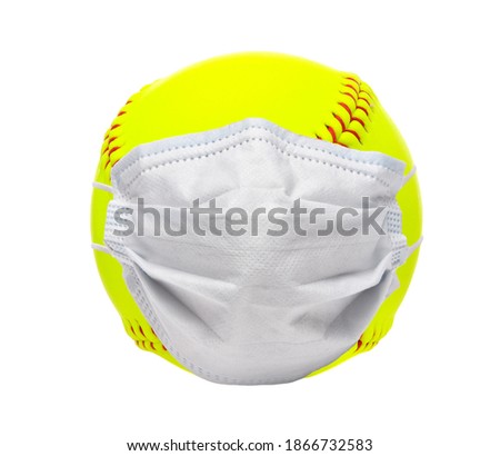 Sports and Covid-19-Concept. Yellow softball with a surgical mask on white background.