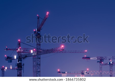 Illuminated and decorated christmas tree standing on arm of very tall tower crane at night  
