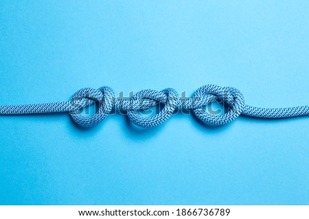 Three knots on a rope on a blue background. Royalty-Free Stock Photo #1866736789