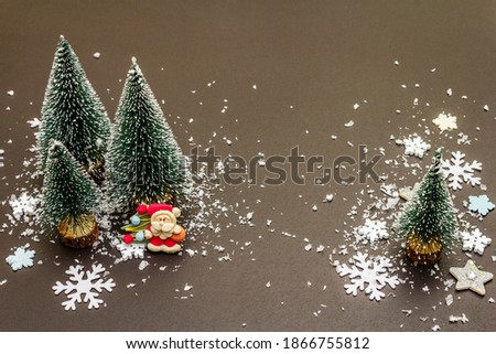 Small decorative Christmas trees with New Year's decor. Santa Claus, snowflakes on black stone concrete background, copy space