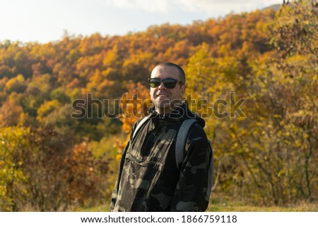 young man with sunglasses surrounded with natire in autumn.