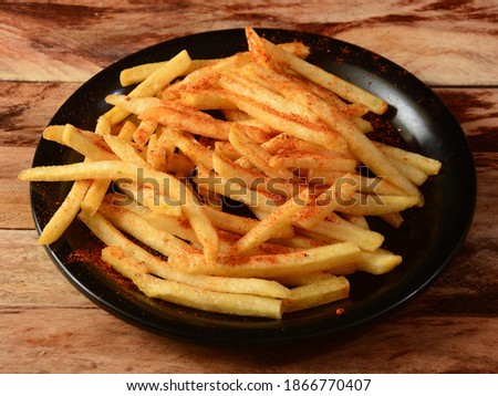Tasty spicy Peri Peri French Fries served in a plate over a rustic wooden background, selective focus Royalty-Free Stock Photo #1866770407
