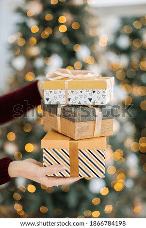 Hands with gift boxes on a gold bokeh background.